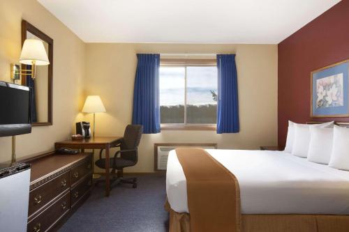 a hotel room with a bed and a desk and a window at Travelodge by Wyndham Motel of St Cloud in Saint Cloud