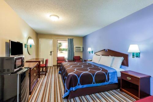 a hotel room with a bed and a television at Super 8 by Wyndham Mt. Pleasant TX in Mount Pleasant