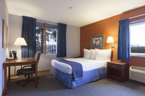 a hotel room with a bed and a desk and window at Travelodge by Wyndham Motel of St Cloud in Saint Cloud
