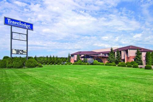 a sign in a field in front of a building at Travelodge by Wyndham Motel of St Cloud in Saint Cloud
