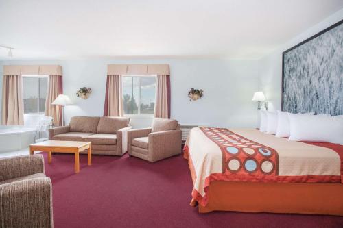 a hotel room with a large bed and a living room at Super 8 by Wyndham Kindersley in Kindersley
