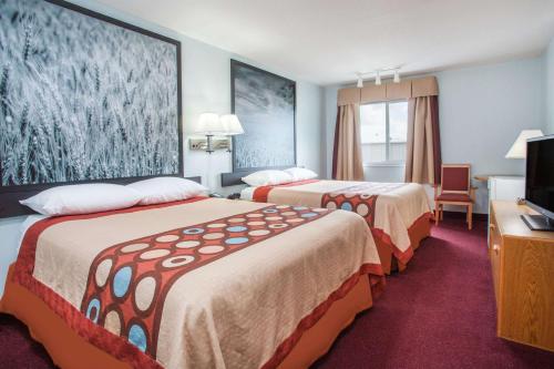 a hotel room with two beds and a flat screen tv at Super 8 by Wyndham Kindersley in Kindersley