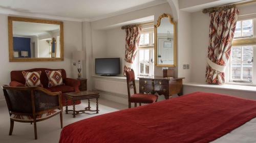 1 dormitorio con 1 cama, 1 silla y TV en The Priory Hotel, en Wareham