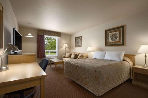 a hotel room with a bed and a couch at Super 8 by Wyndham Dawson Creek in Dawson Creek