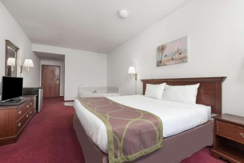 a hotel room with a large bed and a flat screen tv at Super 8 by Wyndham Grayson in Grayson