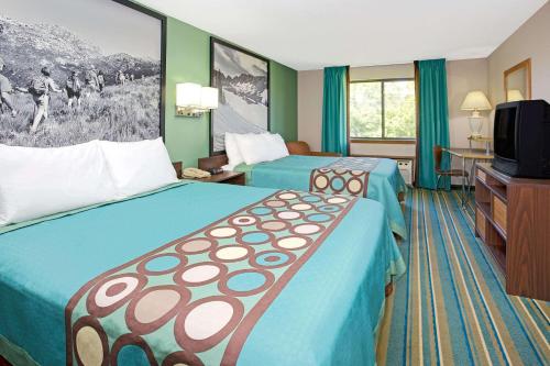 a hotel room with two beds and a flat screen tv at Super 8 by Wyndham Denver Stapleton in Denver