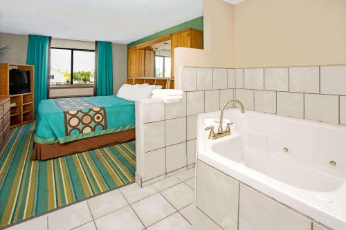 a bathroom with a tub and a bed in a room at Super 8 by Wyndham Denver Stapleton in Denver