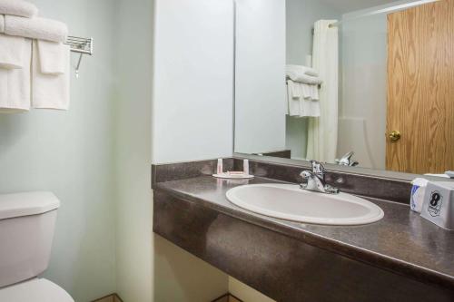 a bathroom with a sink and a toilet and a mirror at Super 8 by Wyndham Kindersley in Kindersley