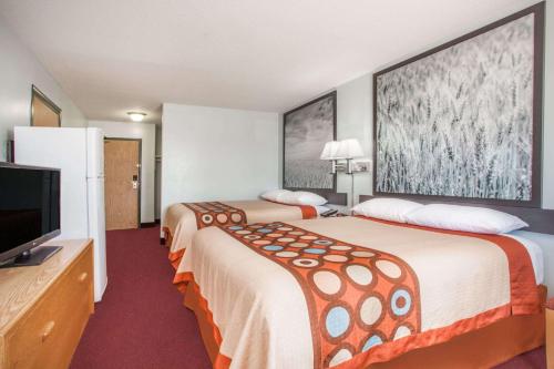 a hotel room with two beds and a flat screen tv at Super 8 by Wyndham Kindersley in Kindersley