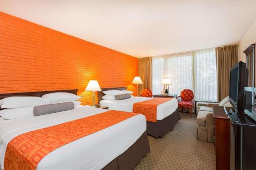 a hotel room with two beds and a flat screen tv at Howard Johnson by Wyndham Williamsburg in Williamsburg