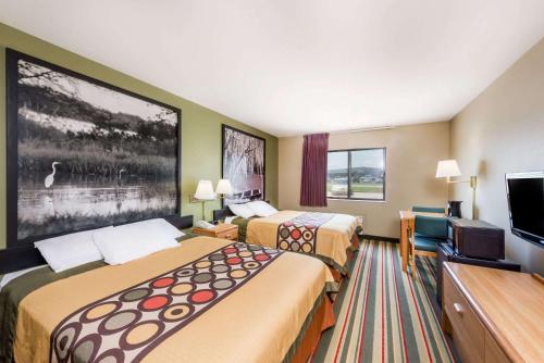 a hotel room with two beds and a flat screen tv at Super 8 by Wyndham Chanute in Chanute