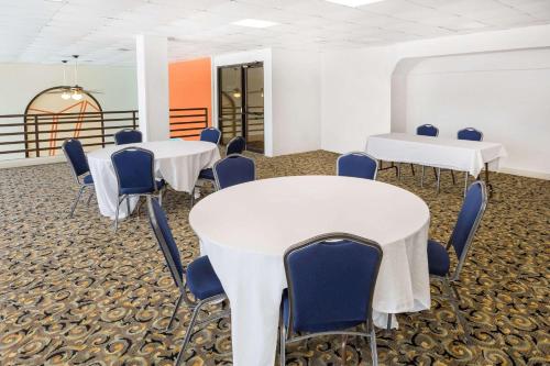 a room with white tables and blue chairs at Howard Johnson by Wyndham Williamsburg in Williamsburg