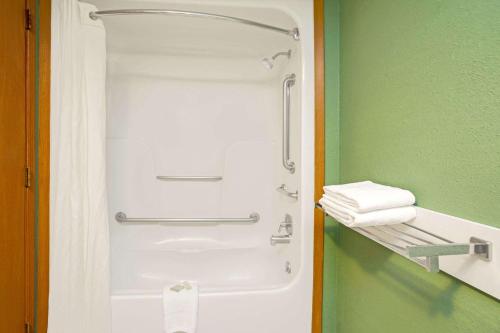 a shower in a green bathroom with towels on a shelf at Super 8 by Wyndham Denver Stapleton in Denver