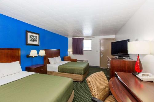 a hotel room with two beds and a desk at Travelodge by Wyndham Great Bend in Great Bend