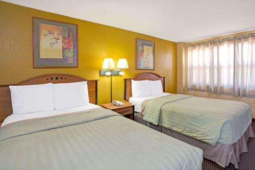 2 camas en una habitación de hotel con paredes amarillas en Travelodge by Wyndham Fort Lauderdale en Fort Lauderdale