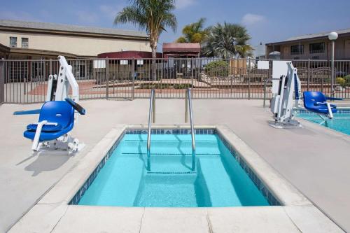 a swimming pool with two blue chairs and a swimming pool at Knights Inn Pico Rivera in Pico Rivera