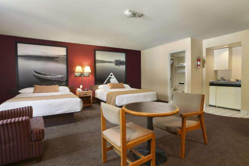 a hotel room with two beds and a table at Super 8 by Wyndham North Bay in North Bay