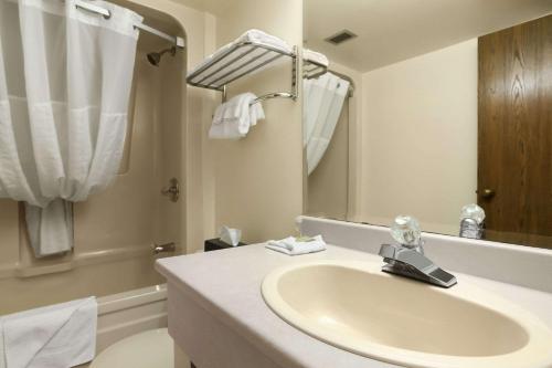 y baño blanco con lavabo y ducha. en Super 8 by Wyndham North Bay en North Bay