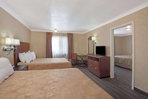 a hotel room with two beds and a mirror at Buena Park Inn in Anaheim