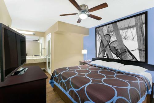 a bedroom with a bed and a flat screen tv at Super 8 by Wyndham Ellenton Bradenton Area in Ellenton