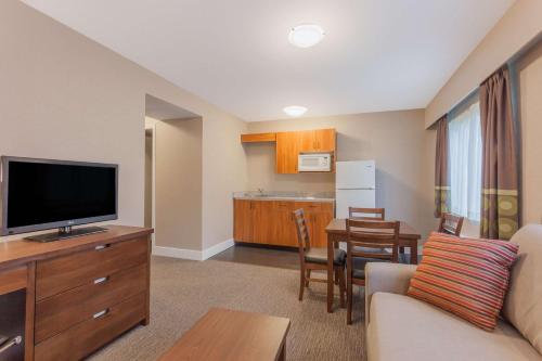 a living room with a couch and a tv and a kitchen at Super 8 by Wyndham Abbotsford BC in Abbotsford