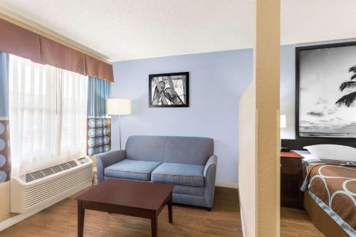 a hotel room with a chair and a bed at Super 8 by Wyndham Ellenton Bradenton Area in Ellenton