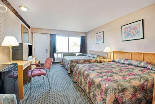 a hotel room with two beds and a television at Weber Inn KItchener in Kitchener