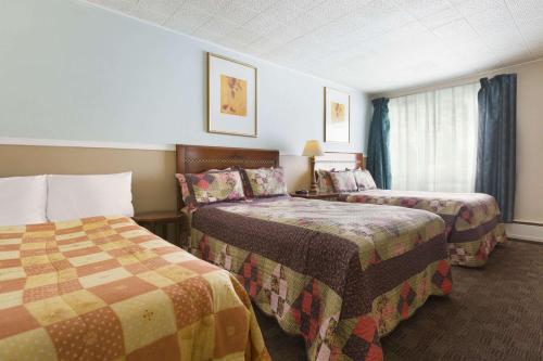 CochraneにあるTravel Inn Cochraneのベッド2台と窓が備わるホテルルームです。