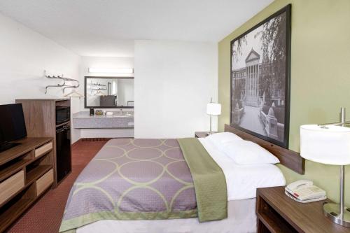 a hotel room with a bed and a television at Super 8 by Wyndham Lafayette in Lafayette
