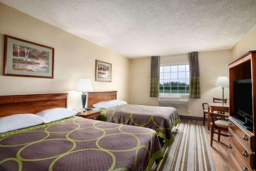 a hotel room with two beds and a flat screen tv at Super 8 by Wyndham Grayville in Grayville