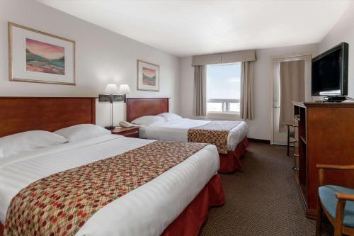 a hotel room with two beds and a flat screen tv at Super 8 by Wyndham Caraquet in Caraquet