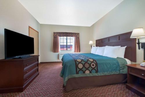 a hotel room with a bed and a flat screen tv at Super 8 by Wyndham Abilene South in Abilene