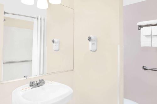 Baño blanco con lavabo y espejo en Super 8 by Wyndham Morton Grove/Chicago, en Morton Grove