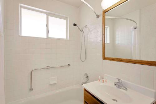Baño blanco con lavabo y espejo en Travelodge by Wyndham Page, View of Lake Powell, en Page