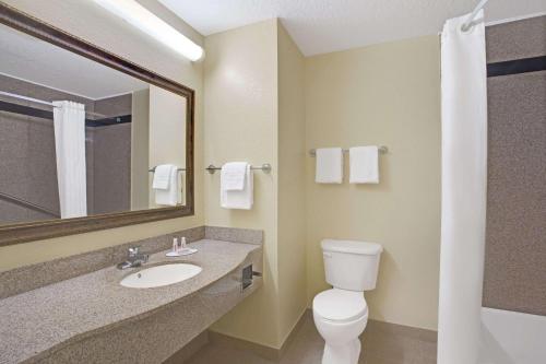 a bathroom with a toilet and a sink and a mirror at Super 8 by Wyndham Daytona Beach in Daytona Beach