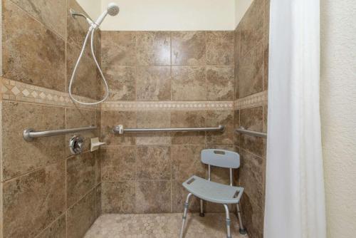 y baño con ducha y silla. en Super 8 by Wyndham Abilene South, en Abilene