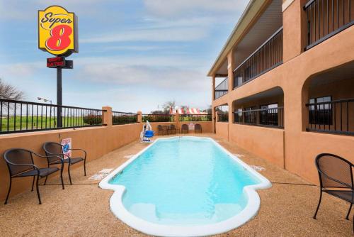 a pool at a hotel with chairs and a sign at Super 8 by Wyndham San Antonio/Riverwalk Area in San Antonio