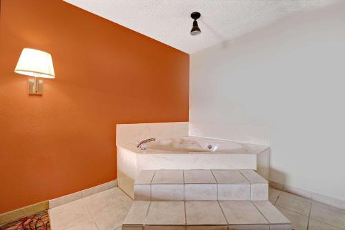 bañera en una habitación con pared de color naranja en Super 8 by Wyndham Dallas South, en Dallas