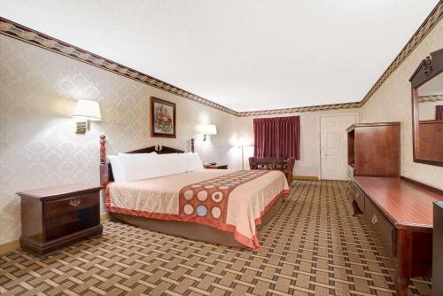 a hotel room with a bed and a television at Super 8 by Wyndham Dallas South in Dallas