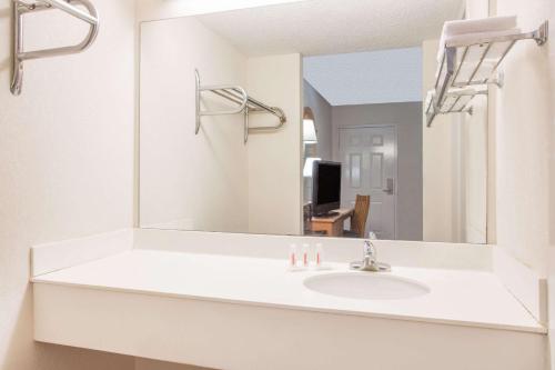 Baño blanco con lavabo y espejo en Super 8 by Wyndham Lavonia, en Lavonia