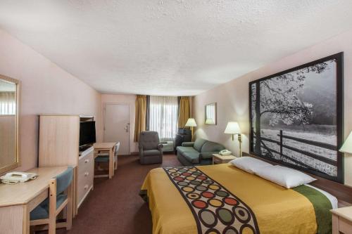 a hotel room with a bed and a living room at Super 8 by Wyndham Jasper TX in Jasper