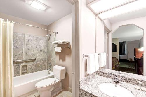a bathroom with a toilet and a sink and a bath tub at Super 8 by Wyndham Richardson Dallas in Richardson