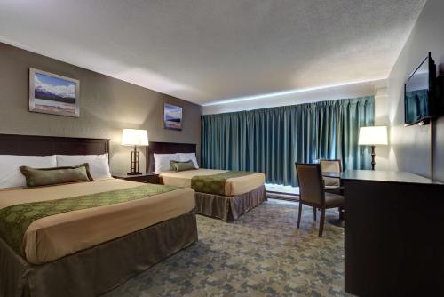 a hotel room with two beds and a flat screen tv at Knights Inn Kamloops in Kamloops