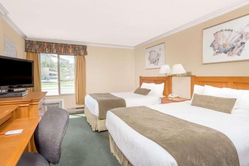 a hotel room with two beds and a flat screen tv at Howard Johnson by Wyndham Downtown Kamloops in Kamloops