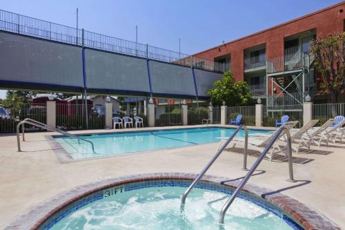 a swimming pool with chairs and a building at Travelodge Inn & Suites by Wyndham Anaheim on Disneyland Dr in Anaheim