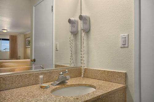 a bathroom with a sink with a phone on the wall at Travelodge by Wyndham Lemoore Near Naval Air Station in Lemoore