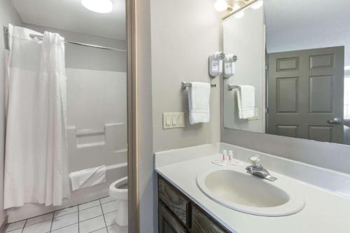 a bathroom with a sink and a toilet and a mirror at Super 8 by Wyndham Clinton in Clinton