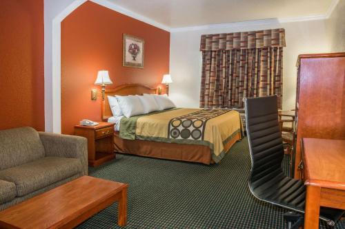 a hotel room with a bed and a chair at Super 8 by Wyndham Brookshire TX in Brookshire