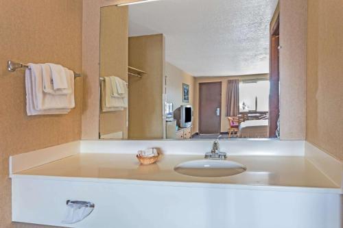a bathroom with a sink and a large mirror at Travelodge by Wyndham Pioneer Villa in Halsey