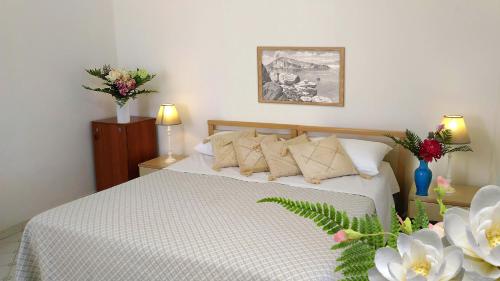 
a bedroom with a bed, a table, and a vase of flowers at Hotel Villa Augustus in Lipari
